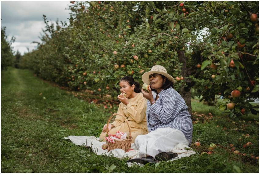 A mother and daughter enjoy a picnic under apple t