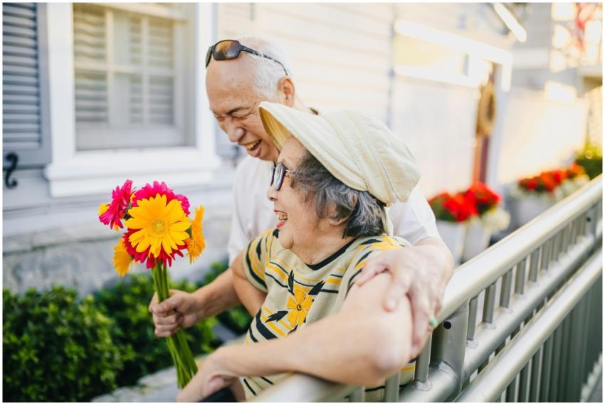 Asian elderly couple holding flowers and smiling t