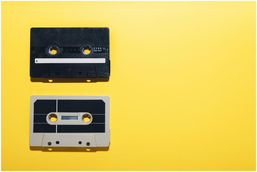 Two vintage cassette tapes on a bright yellow back