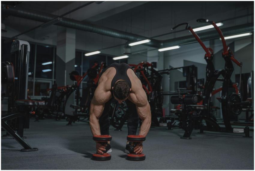 Muscular man in a gym lifting heavy dumbbells show