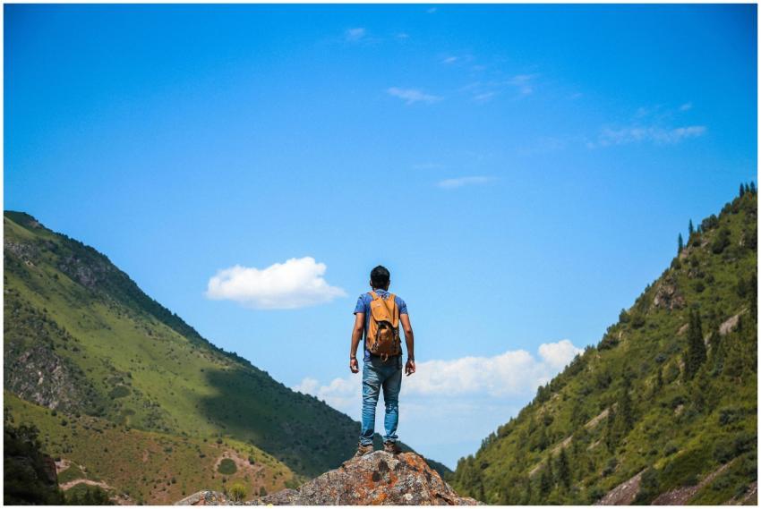 A solo backpacker standing on a rock, admiring the