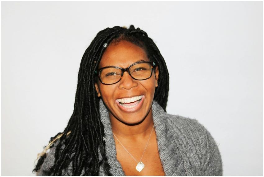 A vibrant portrait of a smiling woman with dreadlo