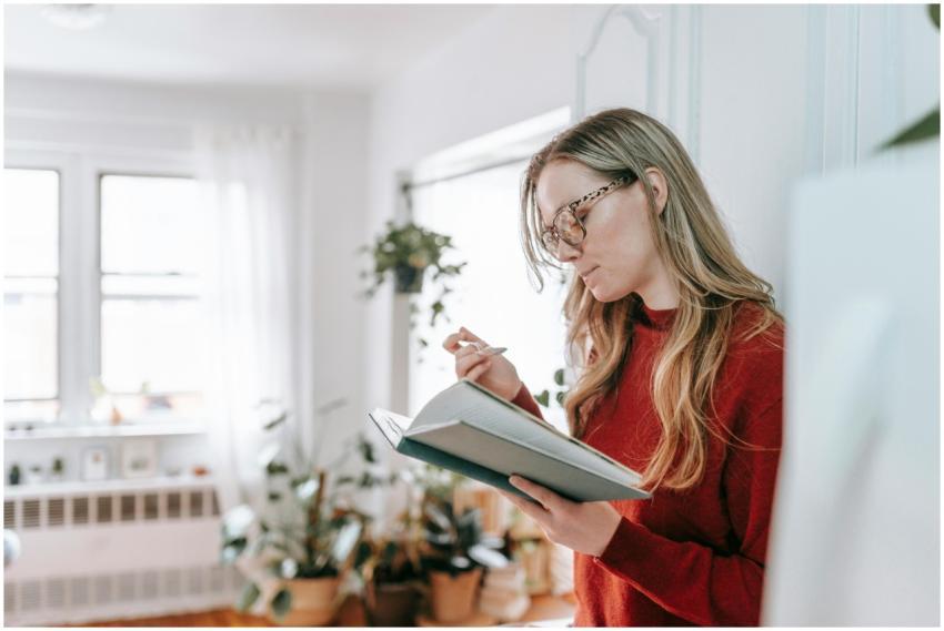 A young woman with eyeglasses reading a notebook i