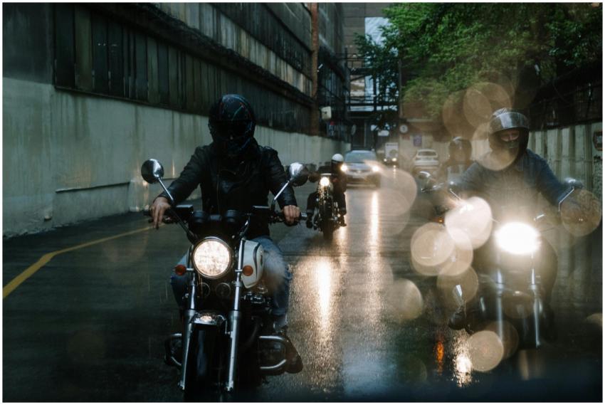 A group of bikers rides motorcycles on a rainy cit