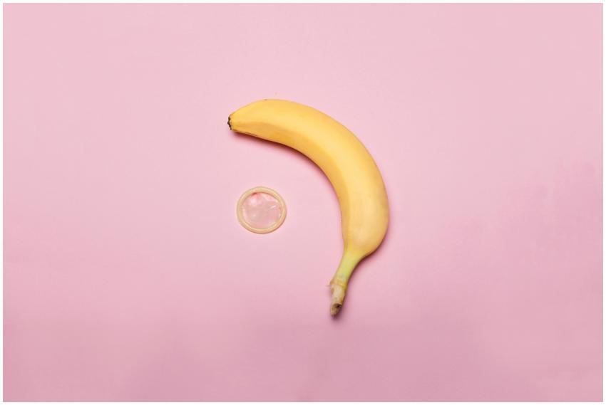 A banana and condom creatively arranged on a pink
