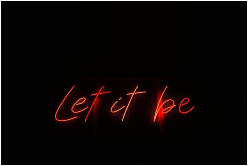 Vibrant neon sign displaying 'Let it be' on a blac