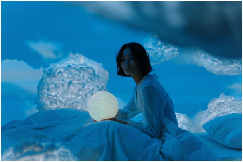 Woman sitting on a bed with a glowing moon lamp am