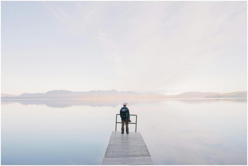 A solitary traveler stands on a dock enjoying the