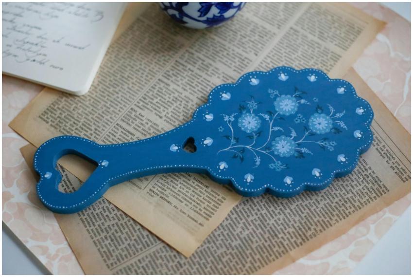 A vintage floral hand mirror placed on aged book p