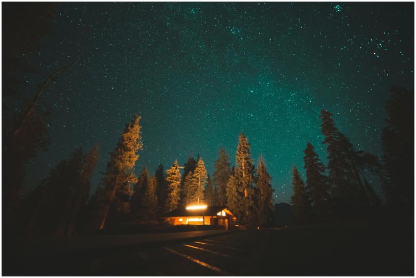 A serene night scene captures a cozy cabin nestled