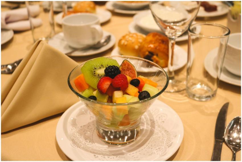 A colorful fruit salad on a table set for dining i
