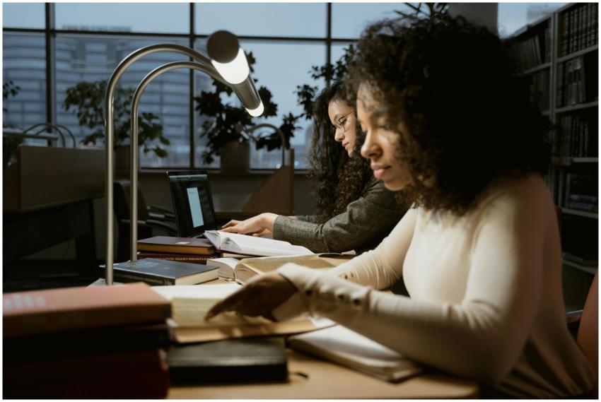 Two women intensely studying in a library setting,