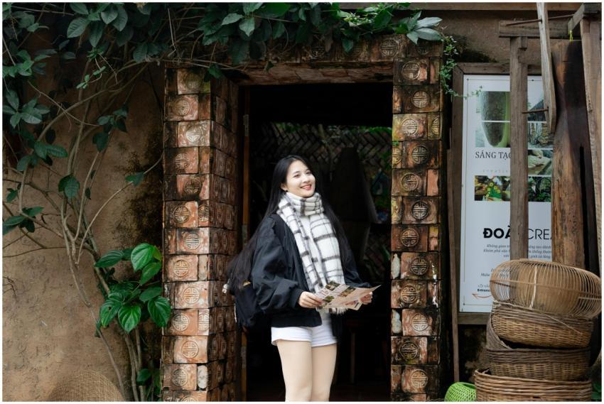 A woman stands at a rustic Vietnamese entrance, ho