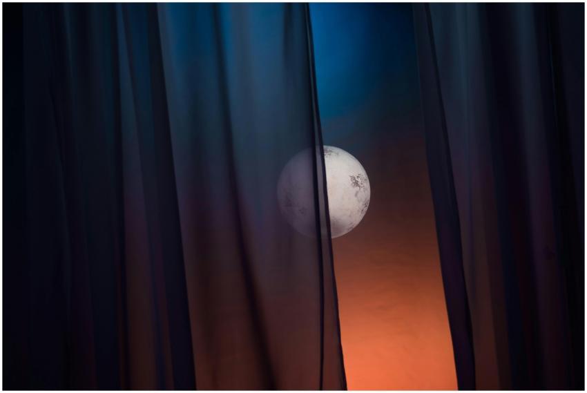 A full moon gently glows through parted dark curta