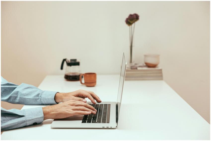 Hands typing on a laptop in a stylish home office,