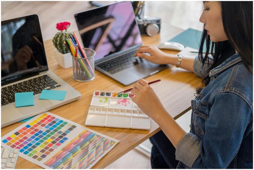 A woman using a laptop and painting with watercolo
