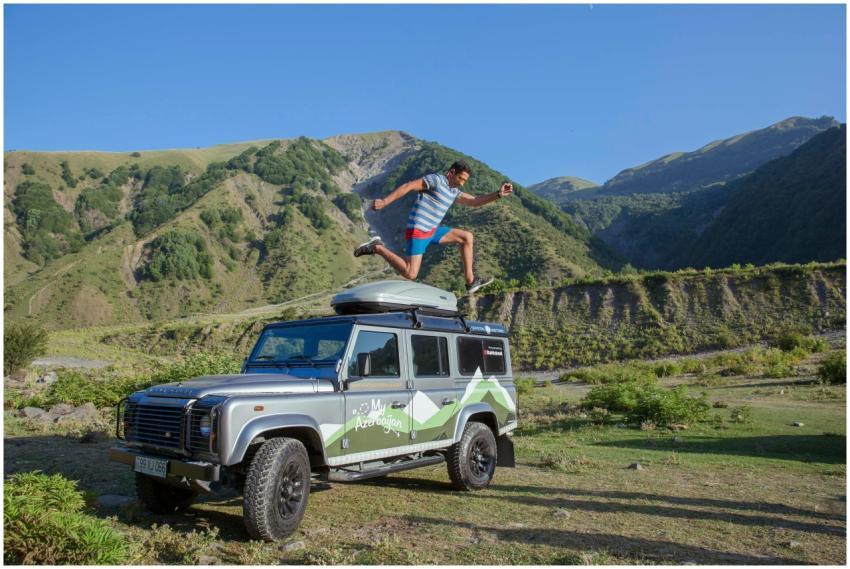 Man jumps on SUV roof in a beautiful mountainous l