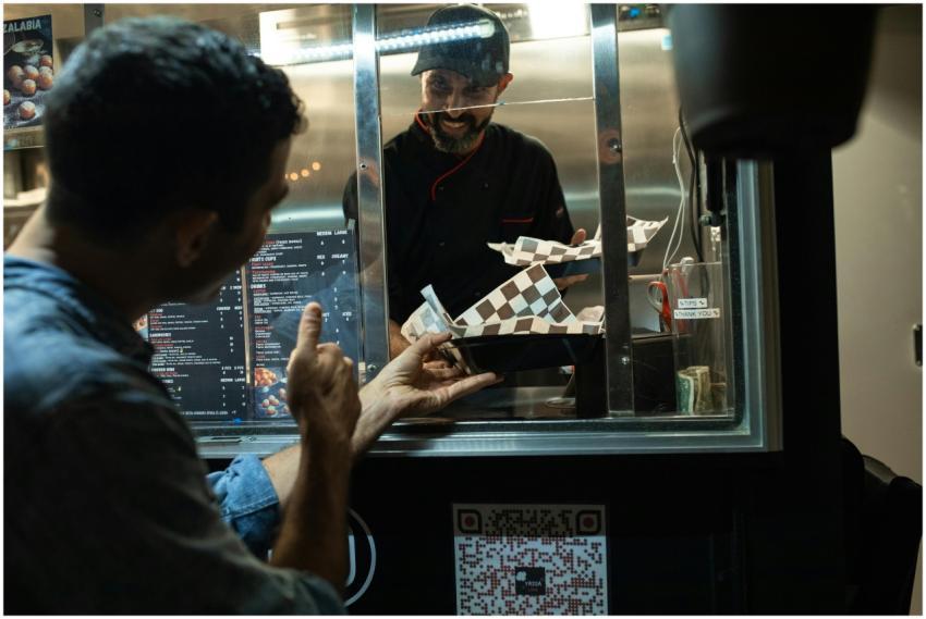 A man is ordering food from a chef inside a street