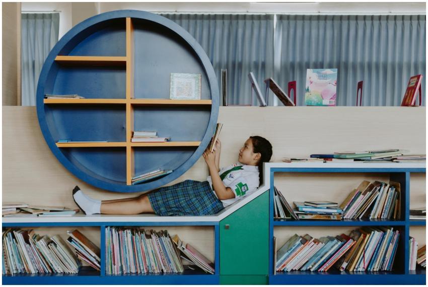 A young girl in a school uniform relaxes and reads