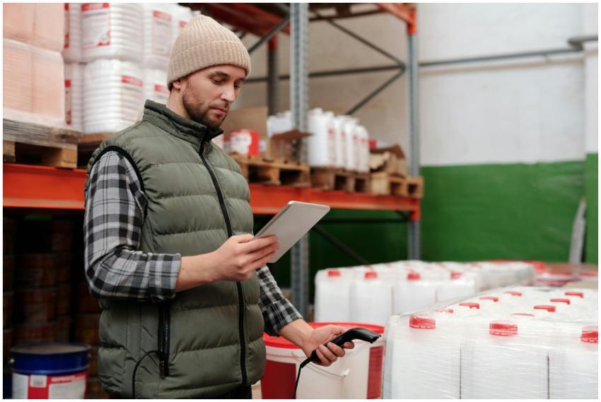 Man managing inventory with tablet in warehouse, f