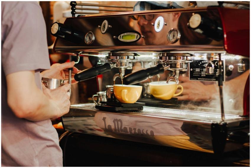 Barista using espresso machine to brew coffee in a