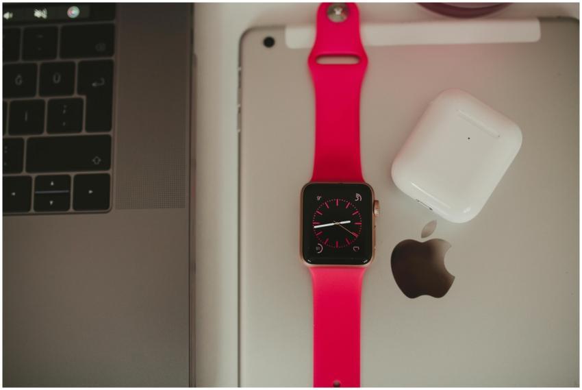 Close-up of a smartwatch, laptop, and earbuds show