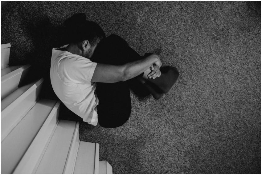 A moody black and white photo of a man sitting on