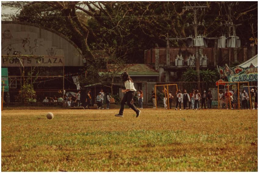 A young girl playing soccer in an open grassy fiel