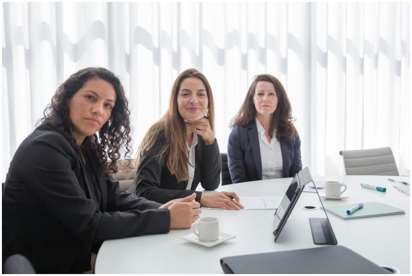 Three businesswomen in a modern office setting, en