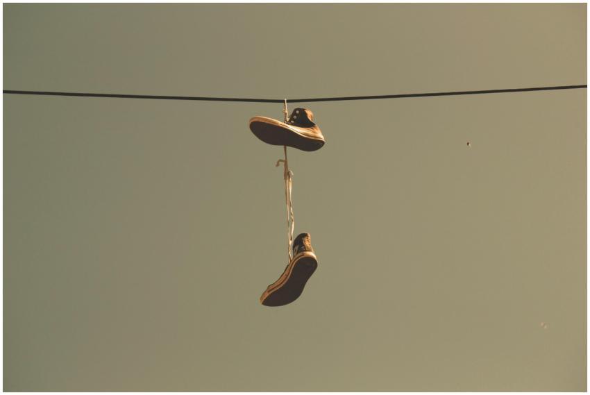Casual sneakers hanging by their laces on a power