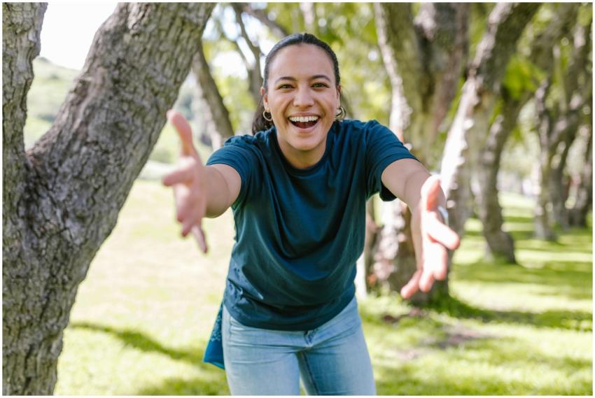 Smiling woman reaching out with open arms in a sun