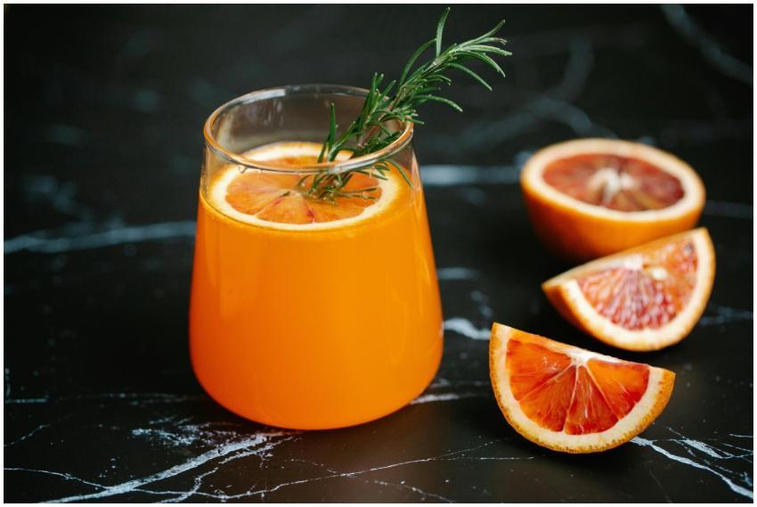 A glass of blood orange juice garnished with rosem