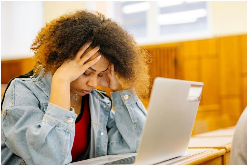 A young woman experiencing a headache while studyi