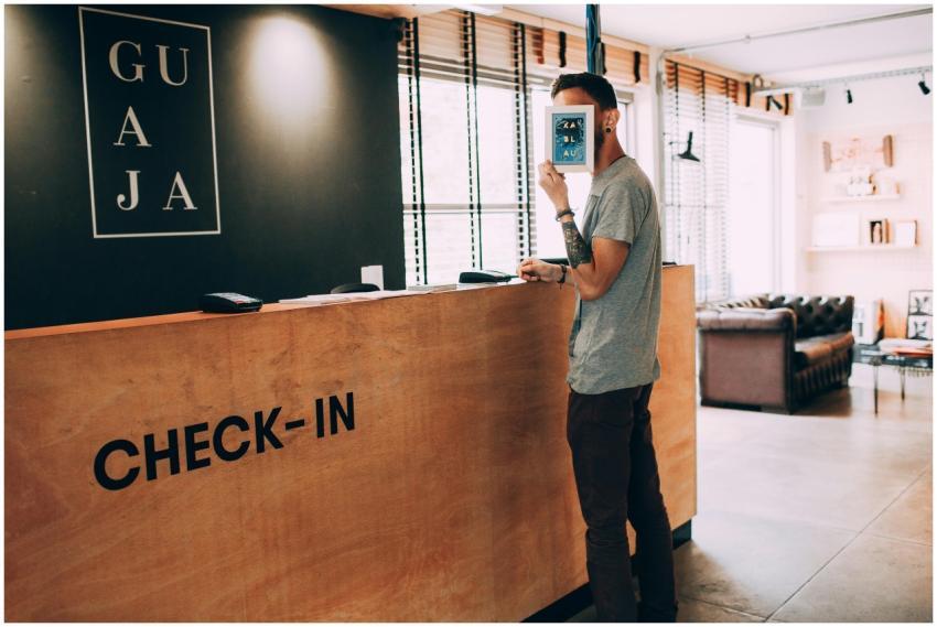 Man standing at a reception desk, holding a book,