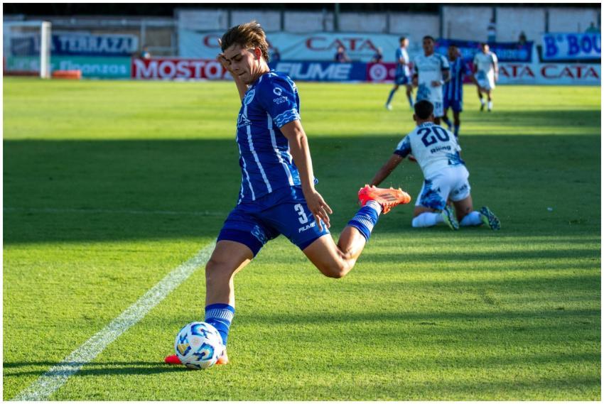 A soccer player in blue kit striking the ball duri