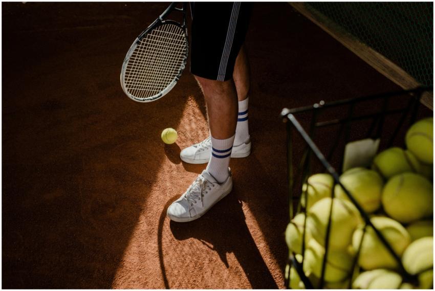 A tennis player stands on a clay court, showing sn