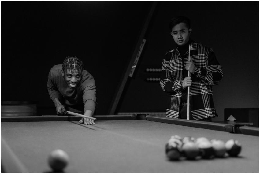 Two men focus intently as they play pool, enjoying