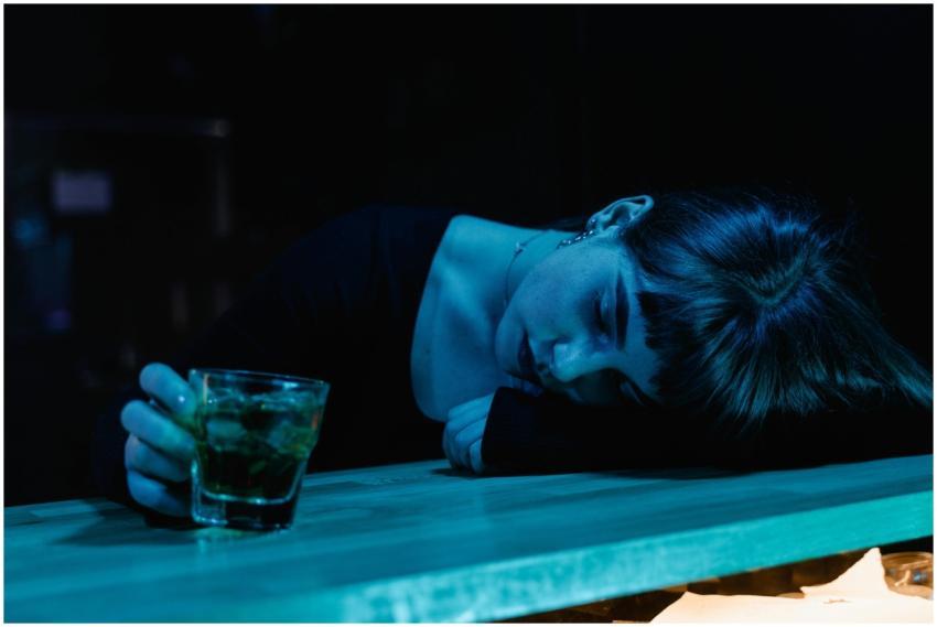 A woman resting her head on a bar table while hold