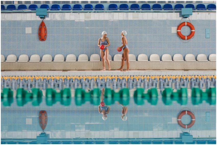 Two swimmers in swimwear holding balls beside an i