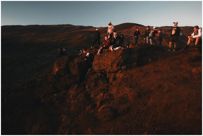 A group of hikers enjoys a sunset view on rocky te
