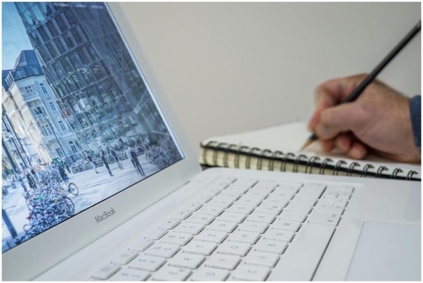 A person taking notes in a notebook beside an open