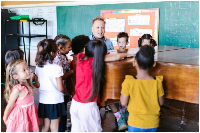 Teacher guiding children in music class around a p