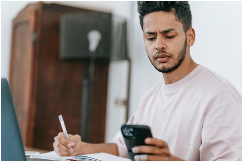 Concentrated ethnic male using mobile phone and ta