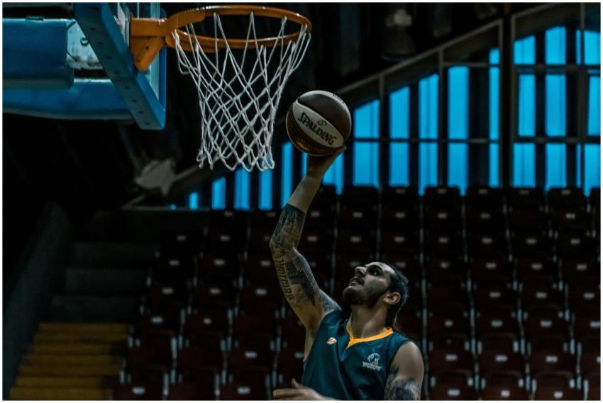 A focused basketball player scores a point in a di