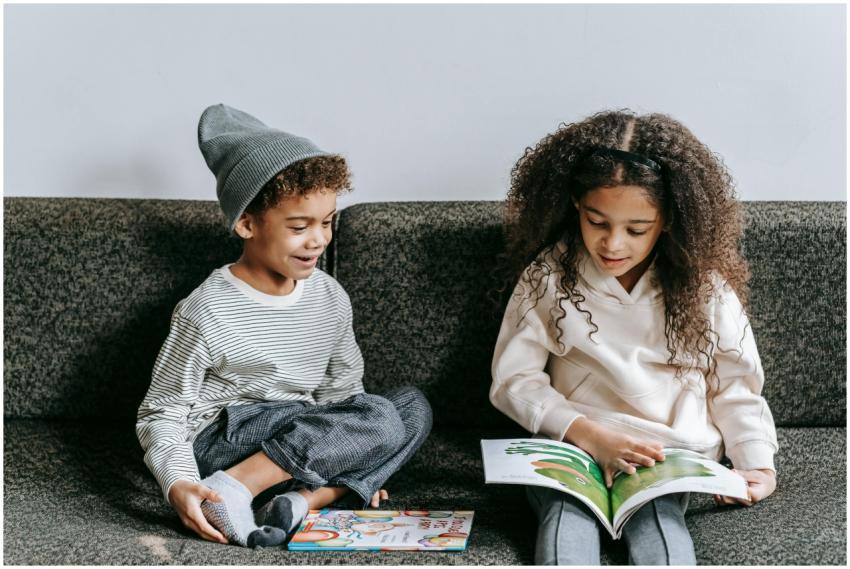 Siblings reading a picture book together indoors,
