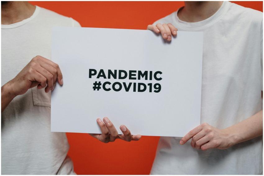 Two people holding a poster with 'Pandemic #COVID1