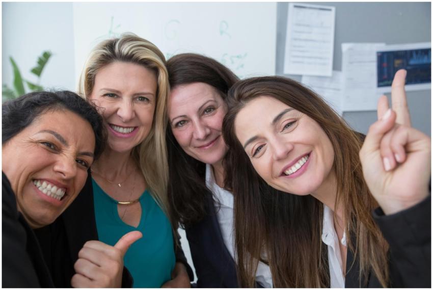 Four female colleagues smiling and posing for a gr