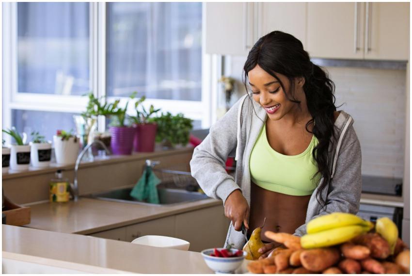 Smiling woman preparing fresh fruit in a sunlit ki