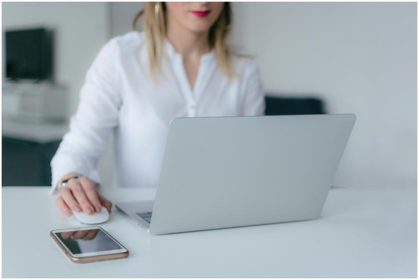 A woman working at a desk using a laptop and smart