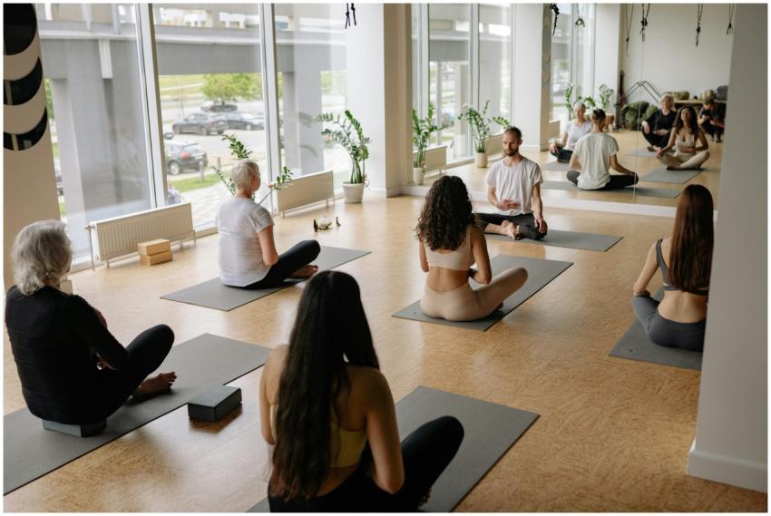 A diverse group practicing yoga indoors on mats, f